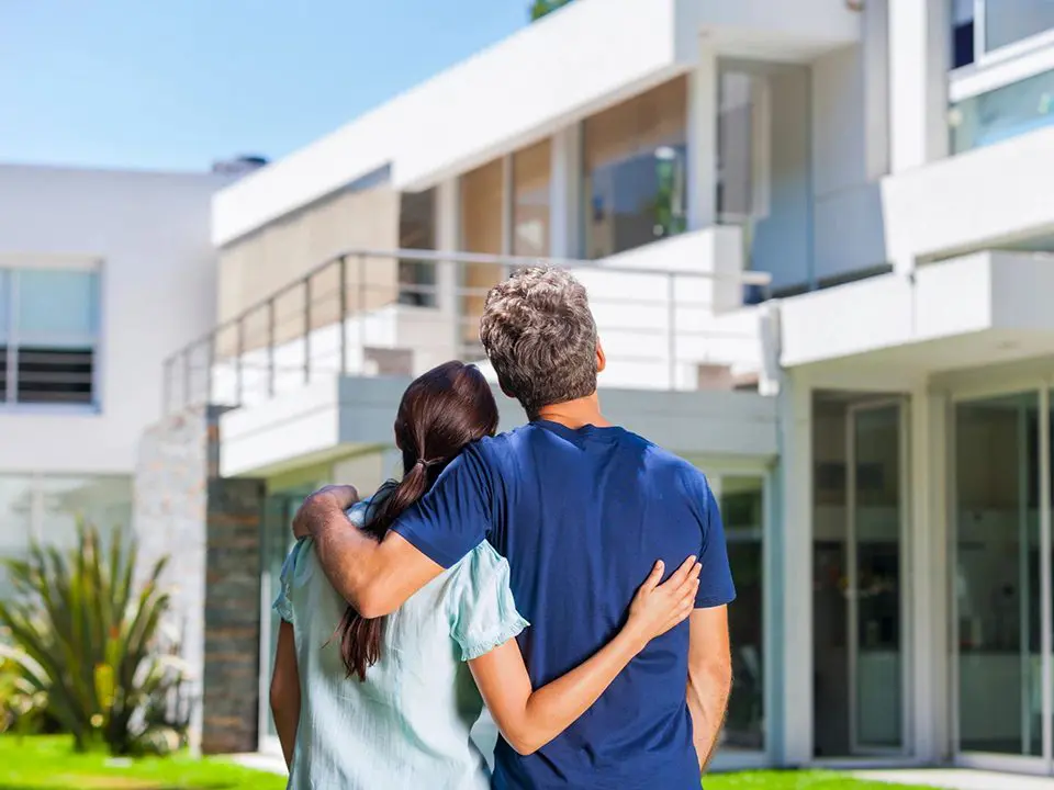 A couple of people that are standing in front of a house