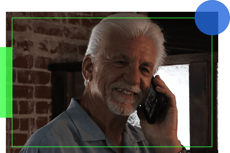 A man with white hair talking on his cell phone.